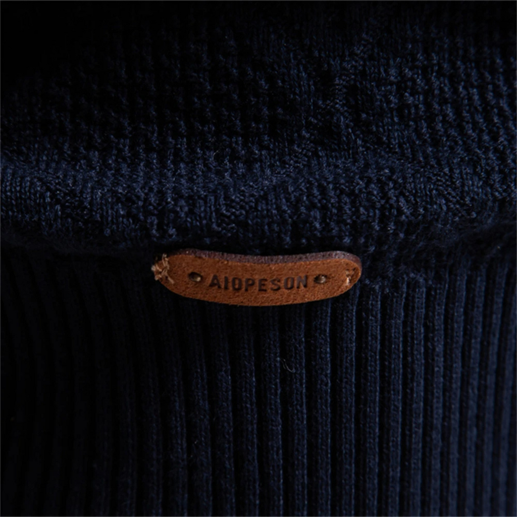 Men's polo sweater hem close-up with leather brand patch on dark knit