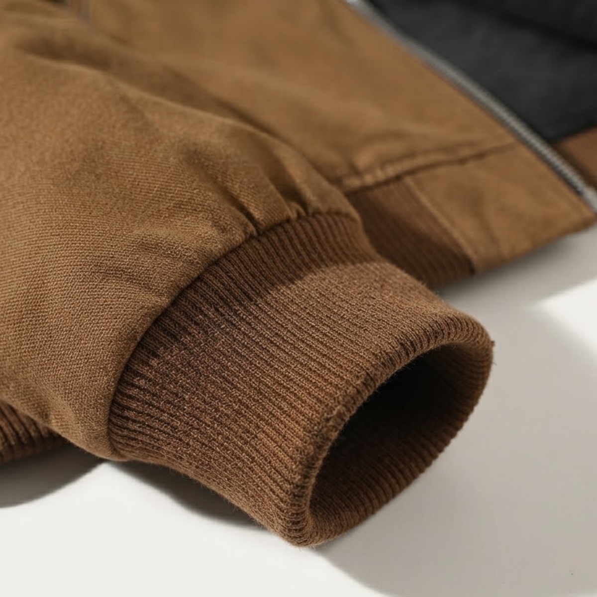 Brown jacket sleeve cuff with knit ribbed trim and smooth fabric seam.