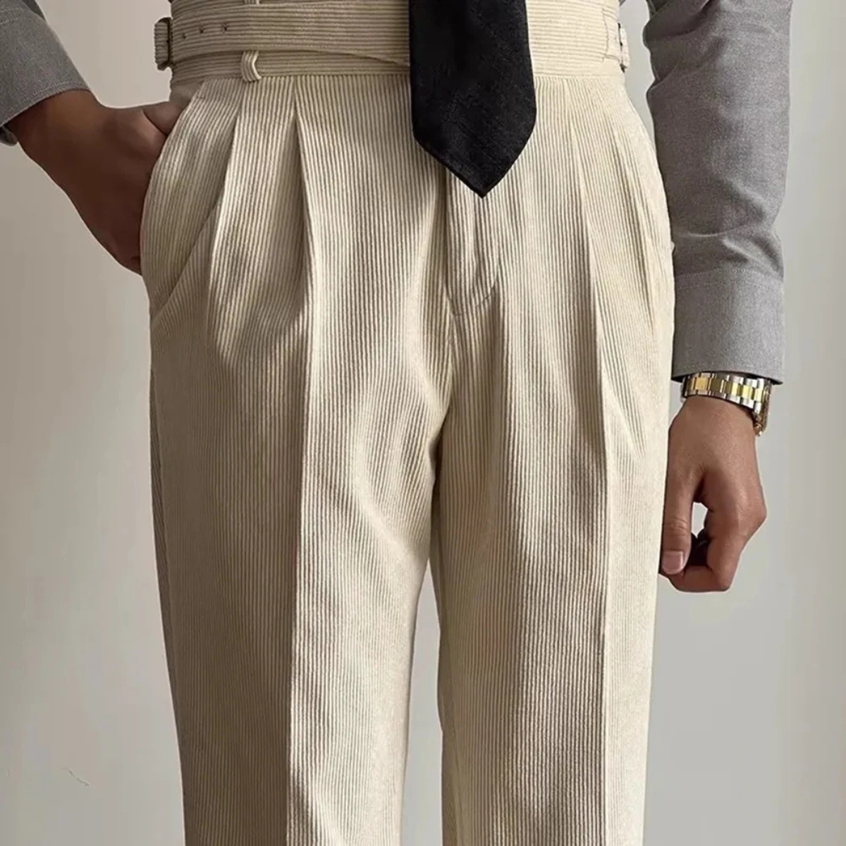 Beige corduroy high-waisted pleated pants with side adjuster tabs and belt loops