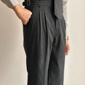 Dark green corduroy high-waisted pleated pants with side adjuster tabs at waistband