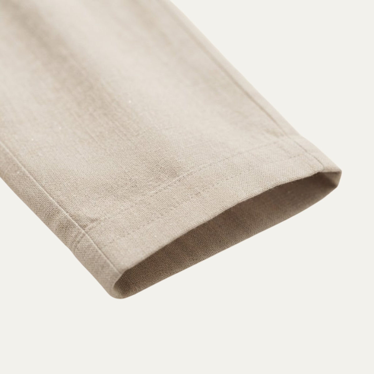 Men’s linen pants cuff hem close-up in light beige, folded stitched edge