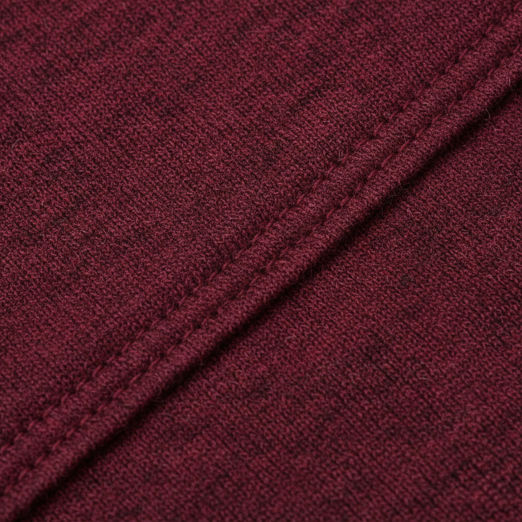 Burgundy knit sweater fabric close-up with visible ribbed texture and stitching