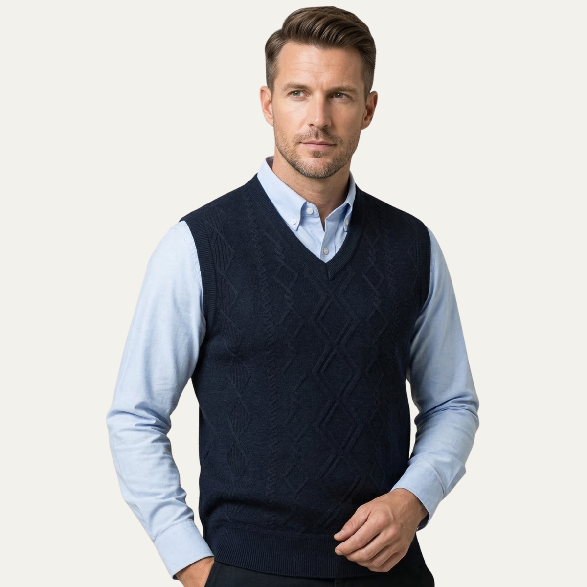 Men's navy v-neck cable knit sweater vest worn over a light blue button-down.