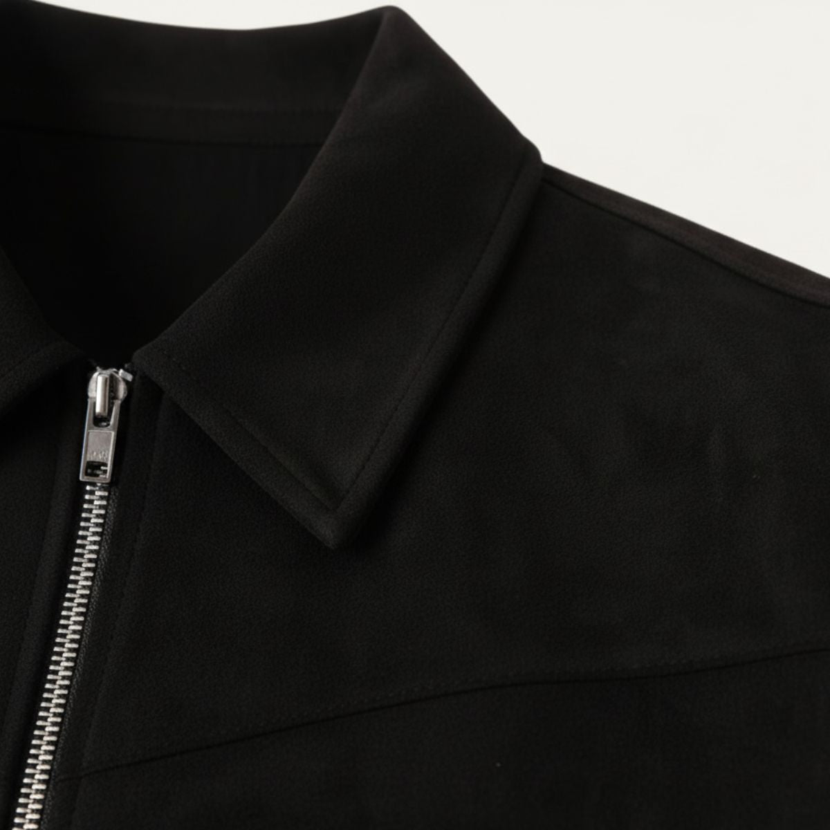 Black suede jacket close-up: point collar and silver zipper with pull tab