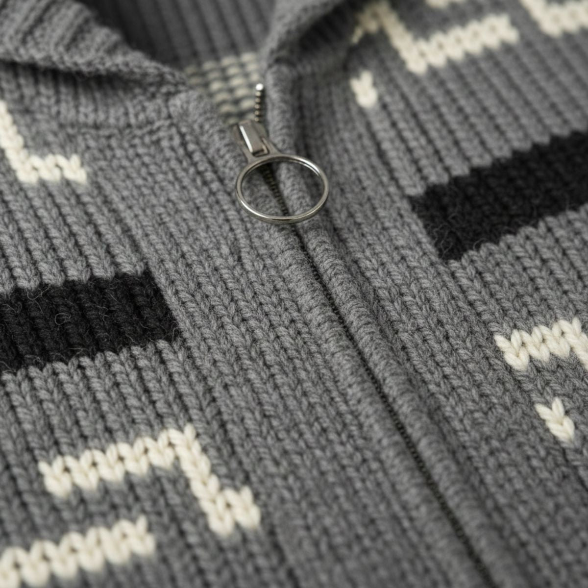 Gray knit cardigan detail: metal ring zipper pull and striped geometric yoke