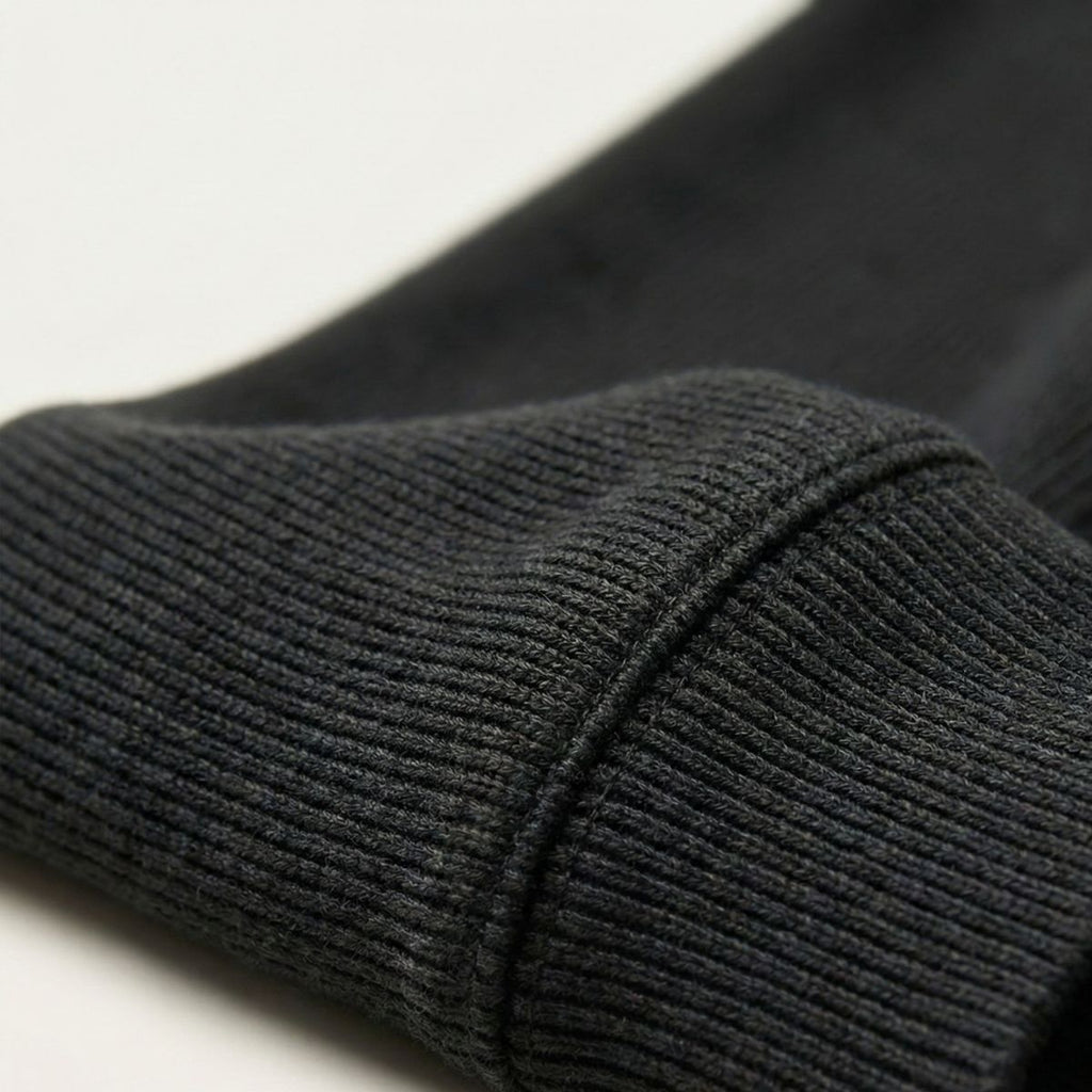 Dark gray knit sweater sleeve cuff with ribbed texture
