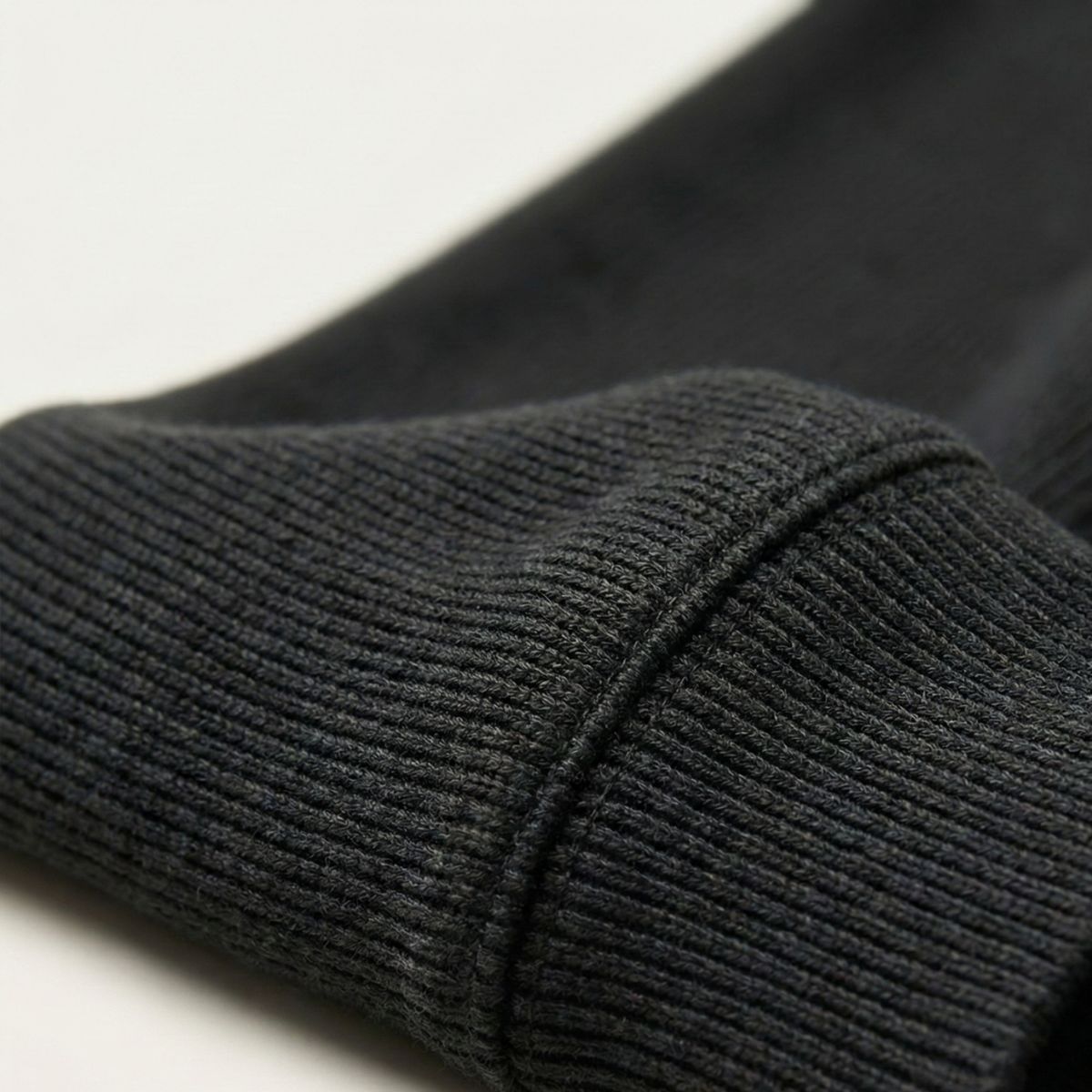 Dark gray knit sweater sleeve cuff with ribbed texture