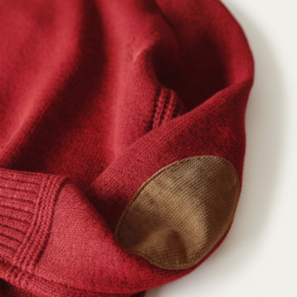 Men's oversized knit sweater in red with tan elbow patches and ribbed cuffs