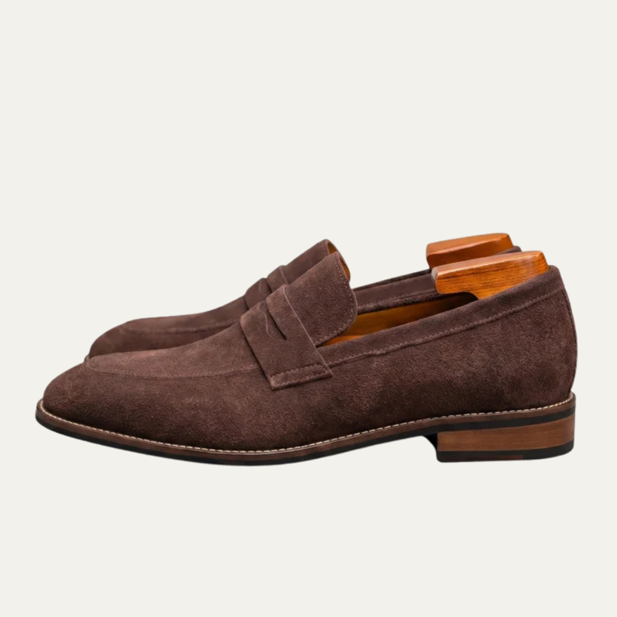 Men's brown suede slip-on penny loafers with side penny strap and low heel.