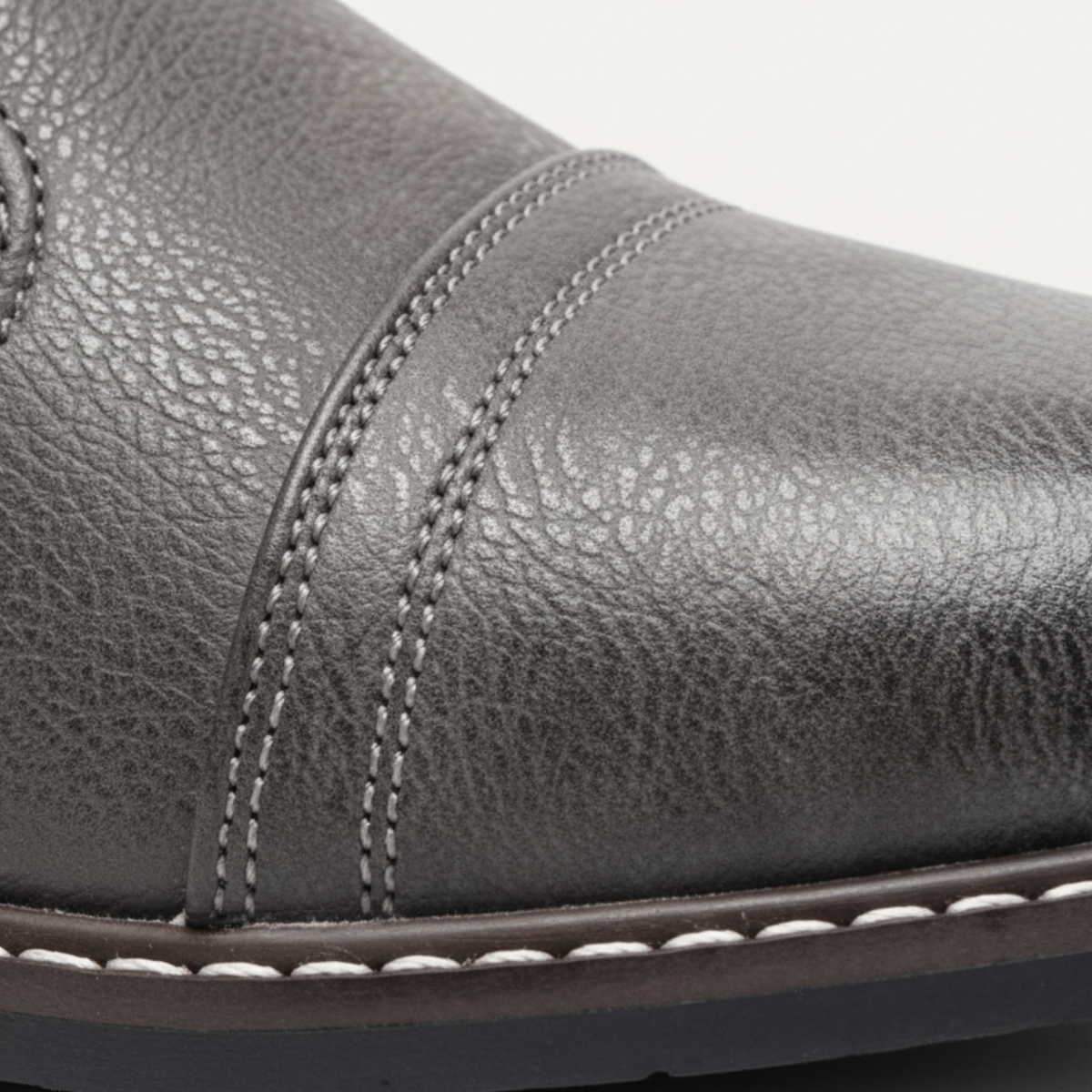 Men's dark gray lace-up ankle boot close-up with textured faux leather and stitched panel