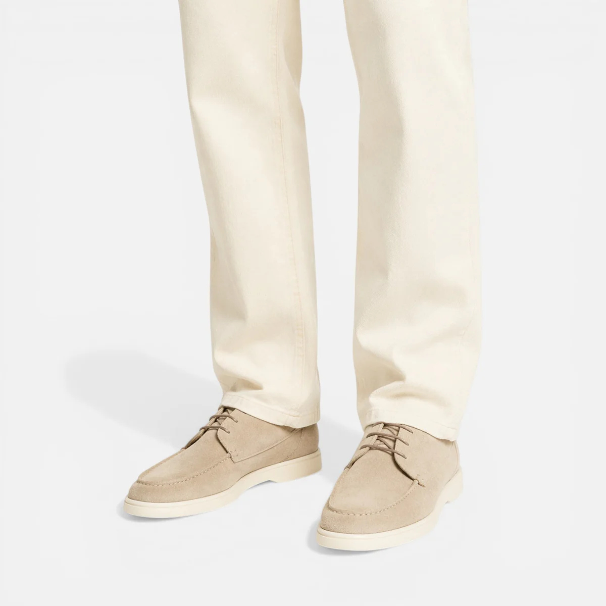 Beige suede lace-up dress shoes worn with cream trousers, low-profile sole