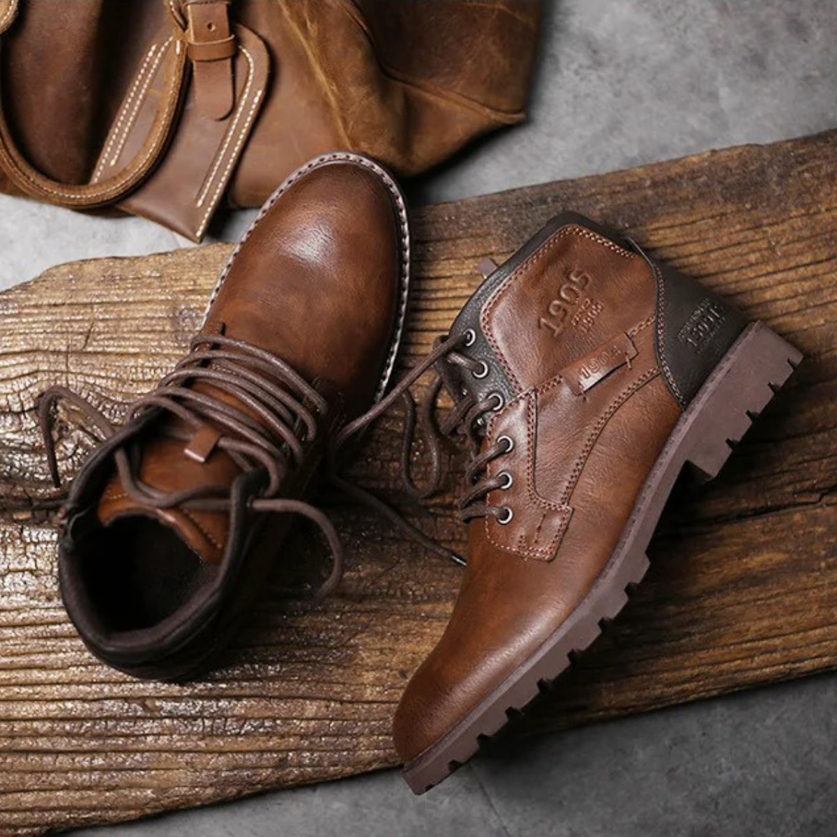 Brown lace-up leather combat boots on wood, lace loops and treaded outsole detail