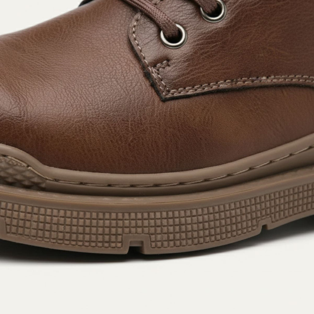 Brown leather boot toe and side, showing eyelets, stitching, and cushioned sole