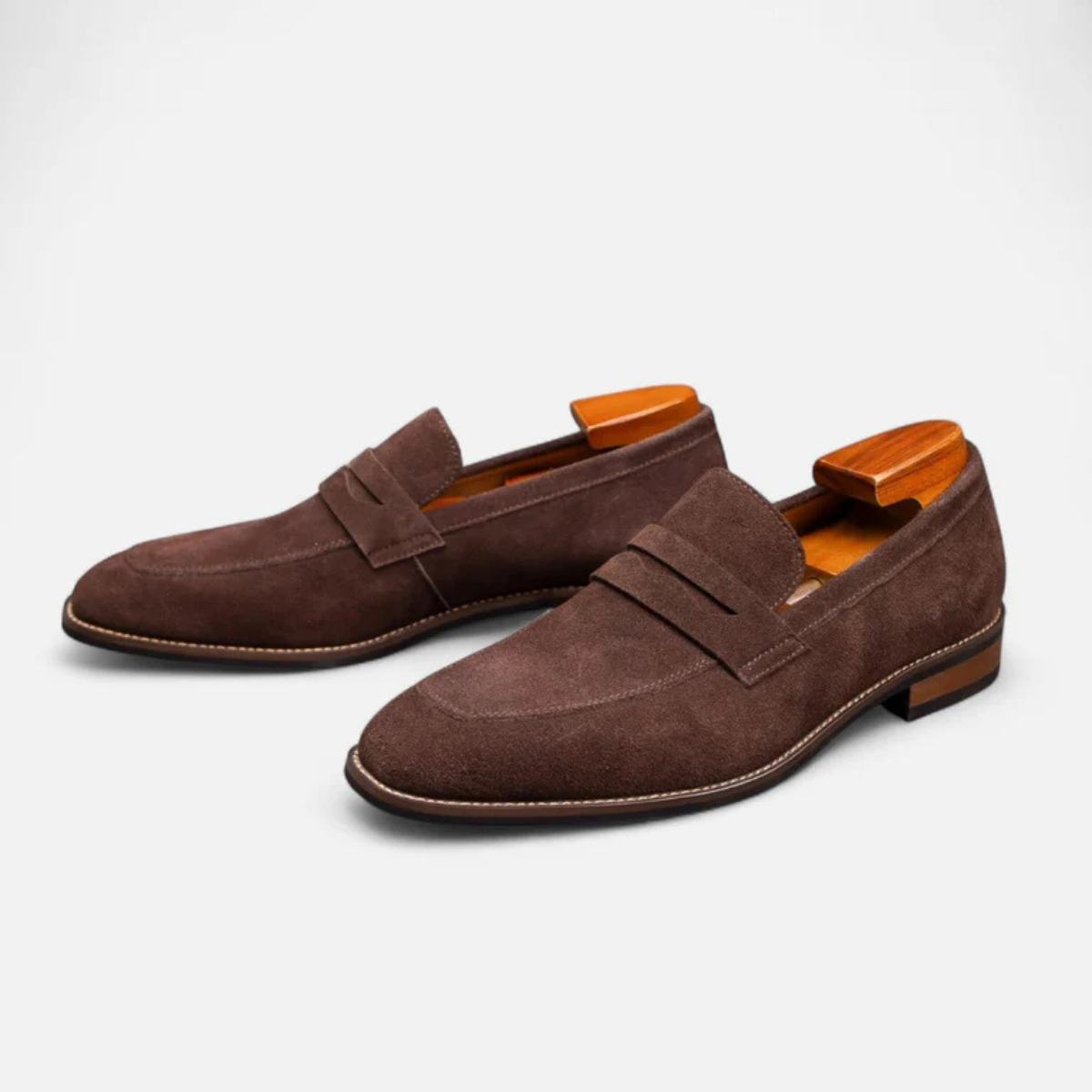 Men's brown suede slip-on penny loafers with side penny strap and low block heel.