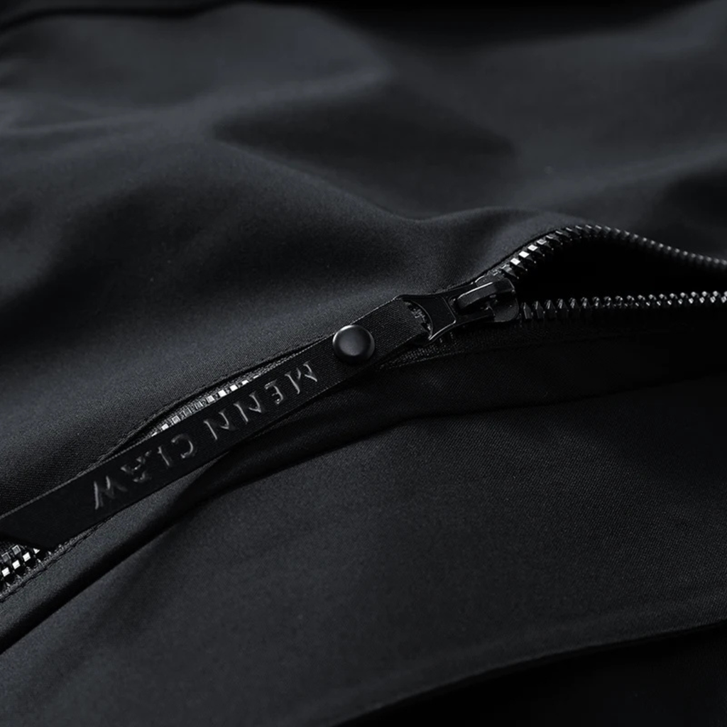 Black waterproof rain jacket close-up of zipper with dark pull tab and stitched track