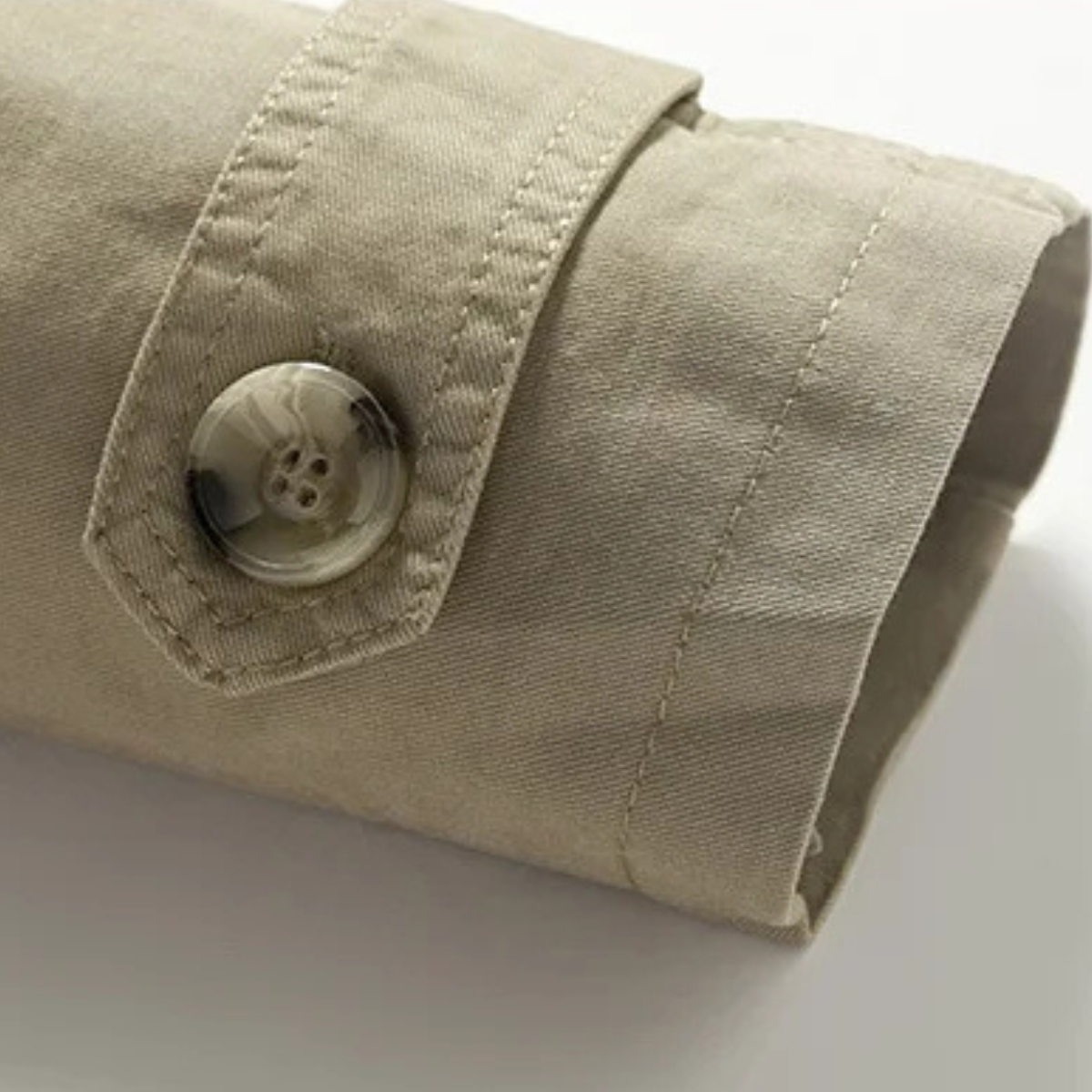 Men's tan trench coat cuff with round button and strap detail