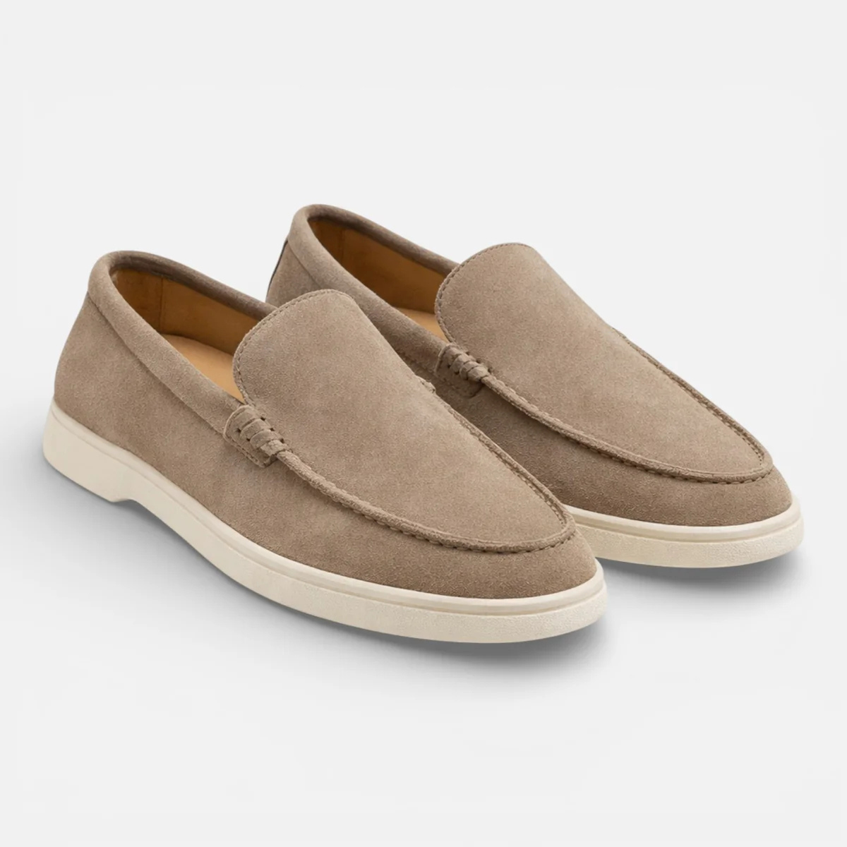 Pair of beige suede slip-on loafers with penny-moc style stitching and white sole