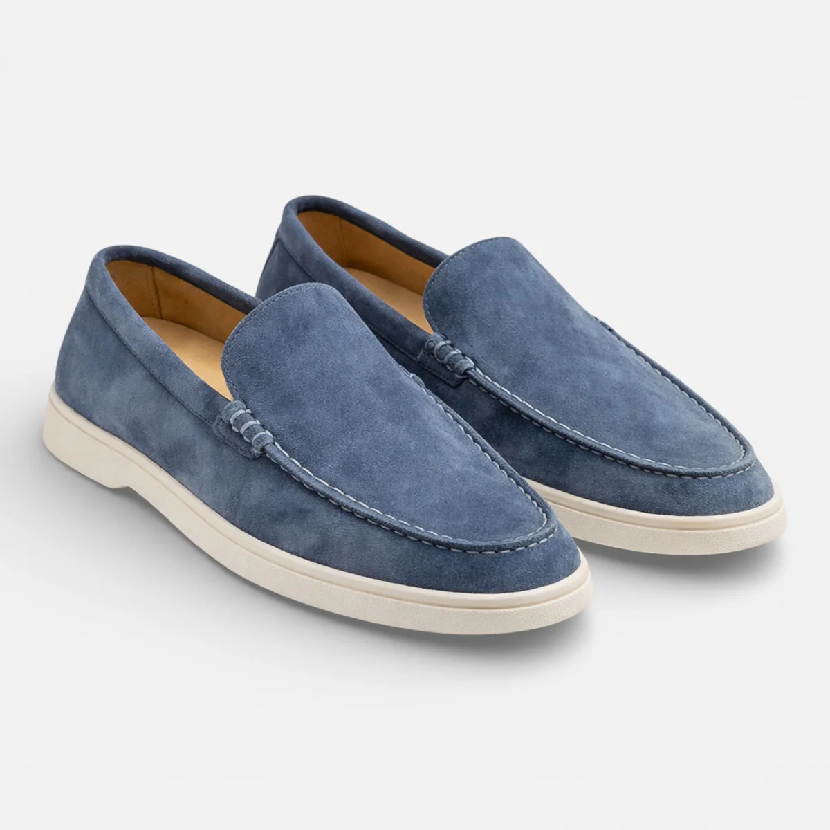 Blue suede slip-on loafers with moccasin stitching and low white rubber sole