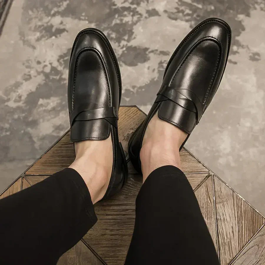 Black leather penny loafers on feet, slip-on style with stitched apron toe
