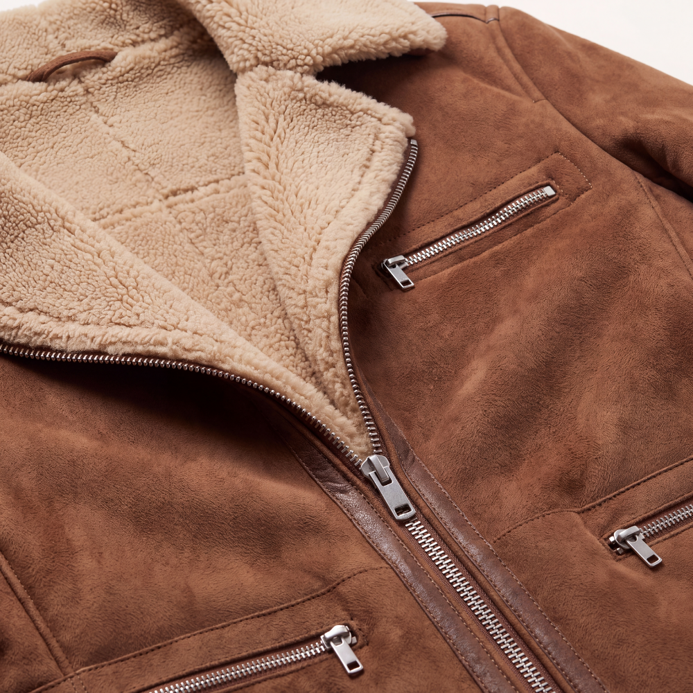 Brown suede sherpa-lined jacket close-up with metal zippers and tan fleece interior