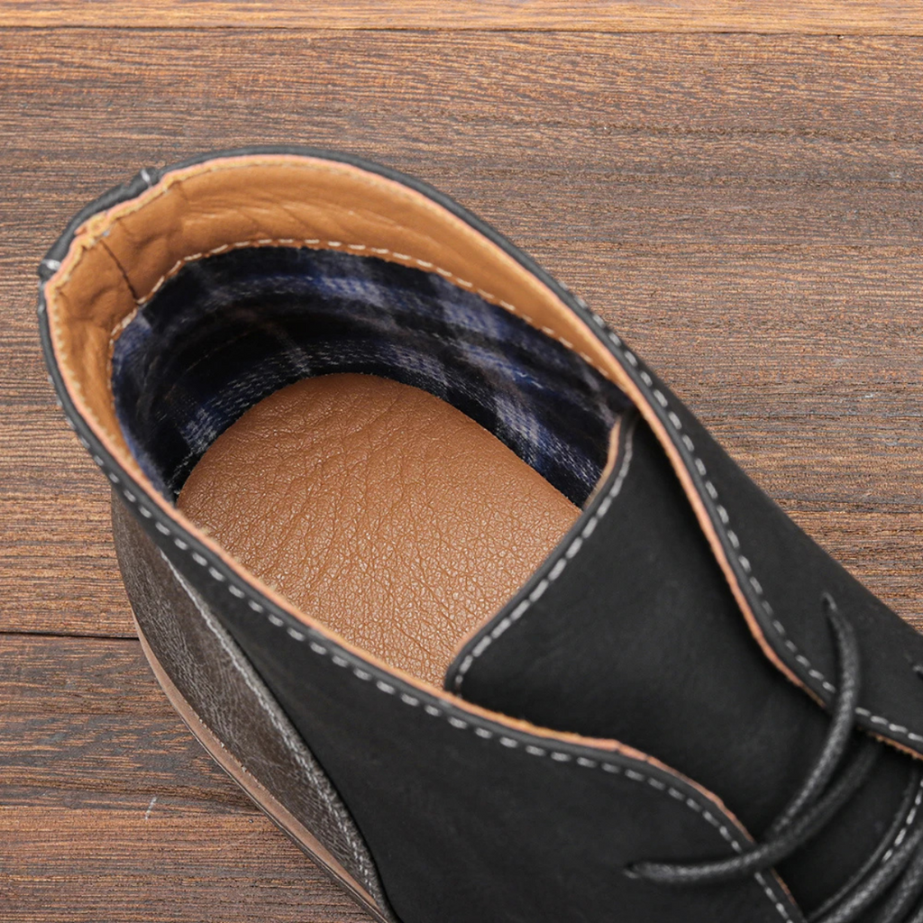 Close-up of black lace-up boot collar with plaid lining and stitched leather trim