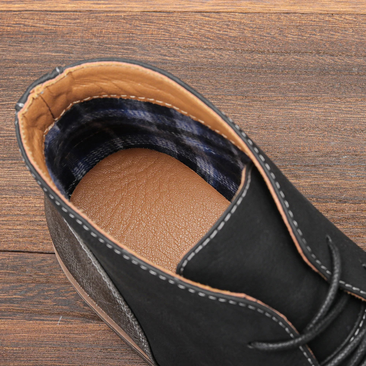 Close-up of black lace-up boot collar with plaid lining and stitched leather trim