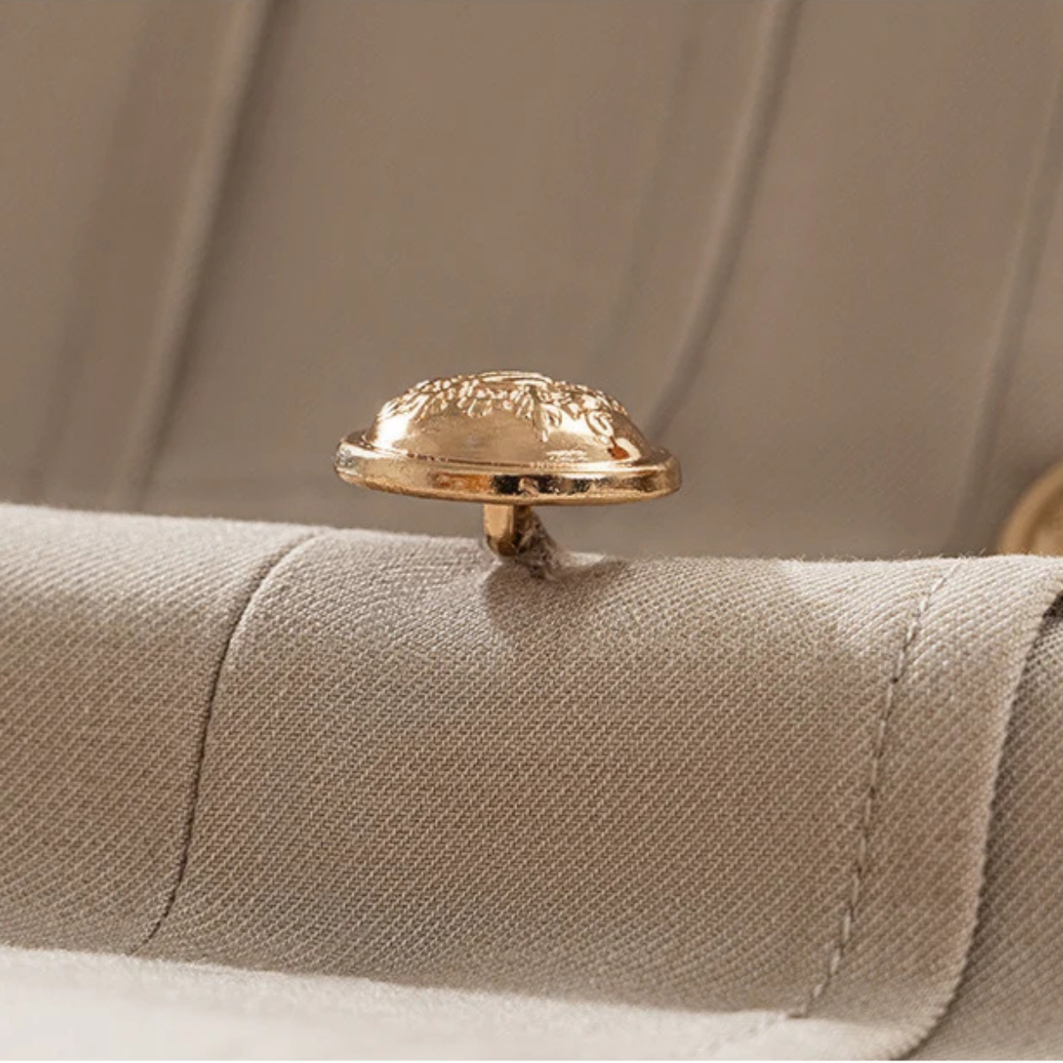 Beige suit jacket cuff close-up with gold-tone button and textured fabric