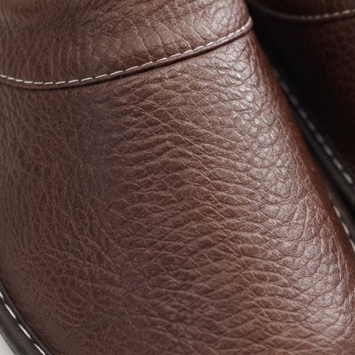 Close-up of brown leather slip-on clog upper with textured grain and seam stitching