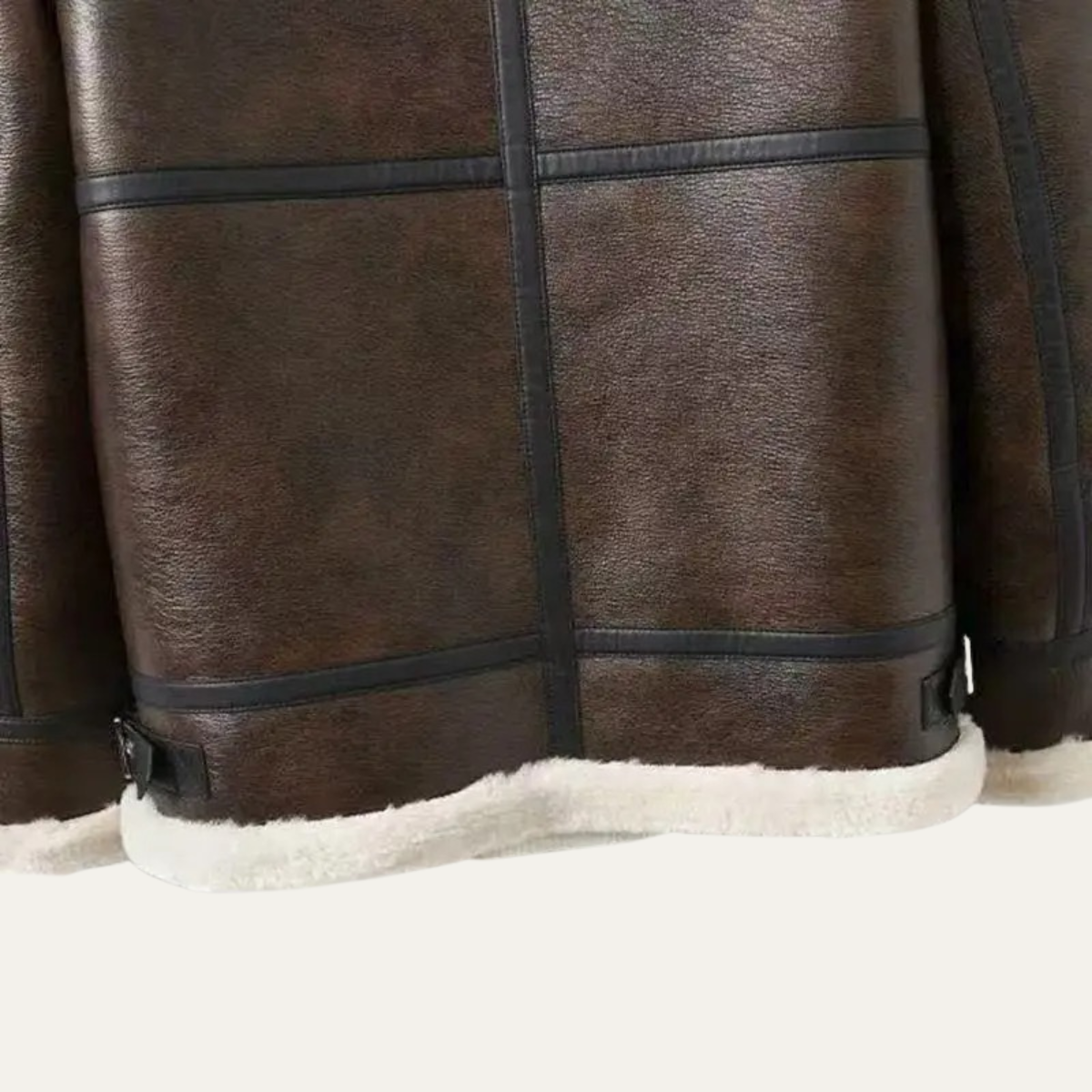 Brown leather jacket hem close-up with cream sherpa lining and side fasteners