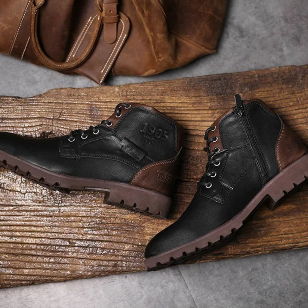 Pair of combat boots: brown lace-up and black side-zip boots on wooden plank