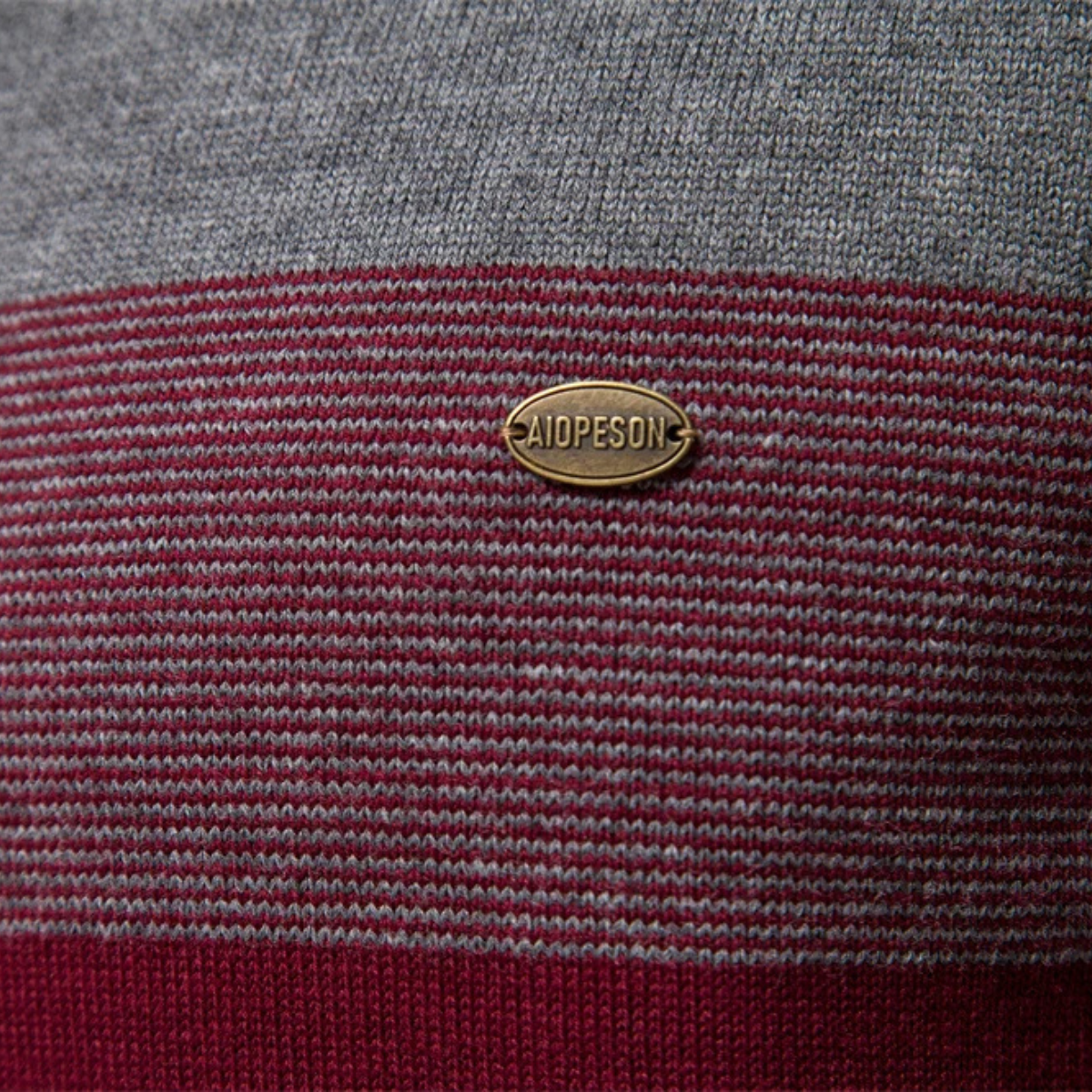 Embroidered oval logo tag on gray and burgundy striped knit sweater
