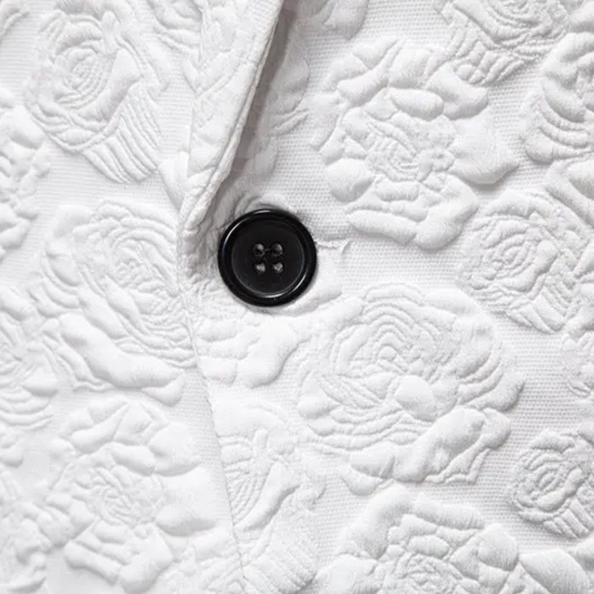 White textured blazer detail with black button and embossed fabric pattern