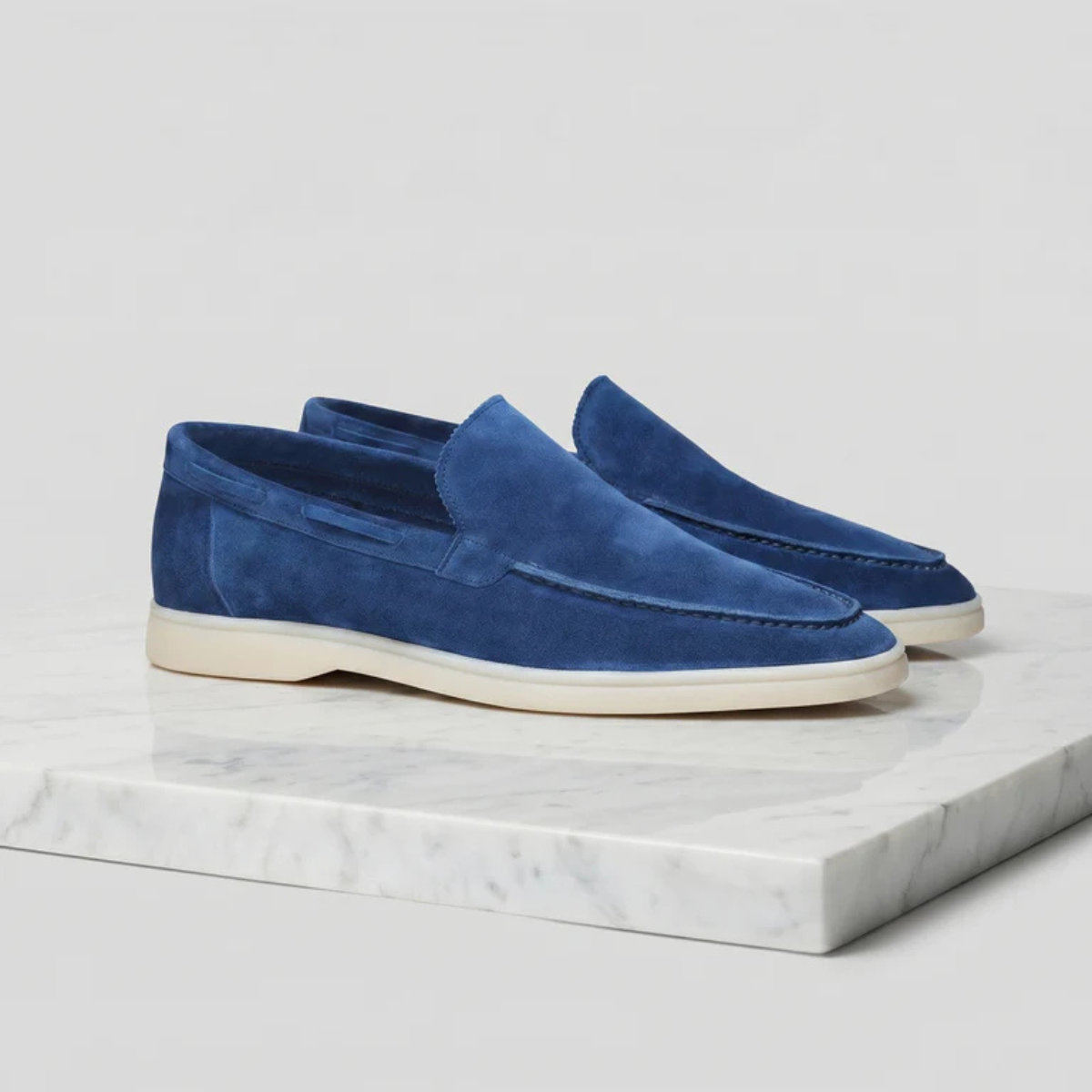 Men's blue suede slip-on loafer with moc-style stitching and white rubber sole