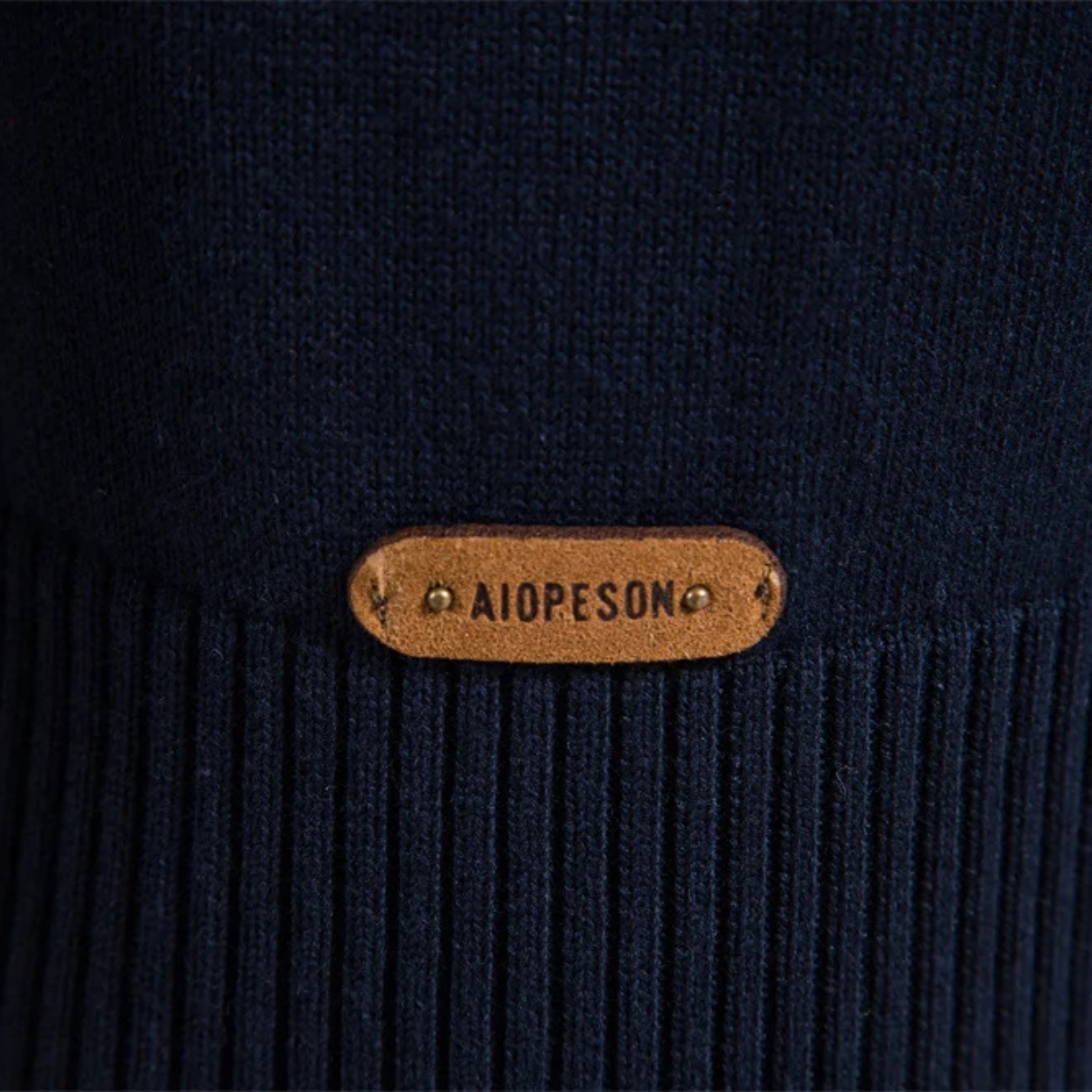 Gold oval logo zipper pull on navy ribbed knit sweater