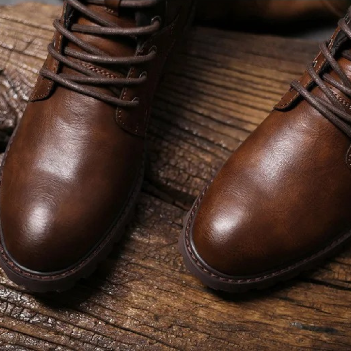 Brown leather lace-up boots close-up, rounded toe and thick sole edge on wood plank