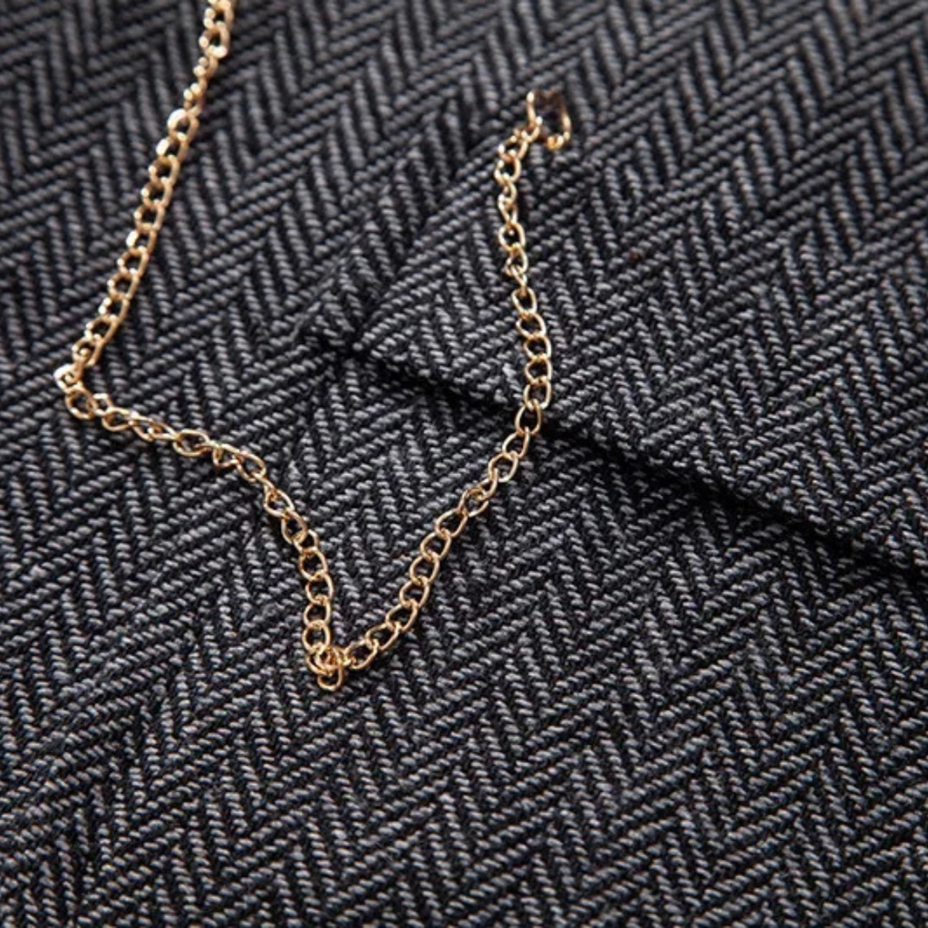 Gold chain accessory detail on dark gray tweed vest fabric