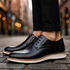 Black lace-up oxford shoes with perforated finish and white sole worn outdoors