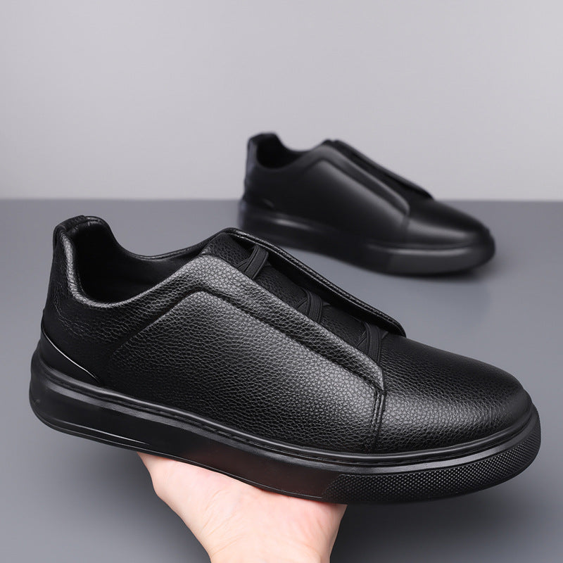 Black low-top sneakers with elastic lace strap, textured upper, front angle.