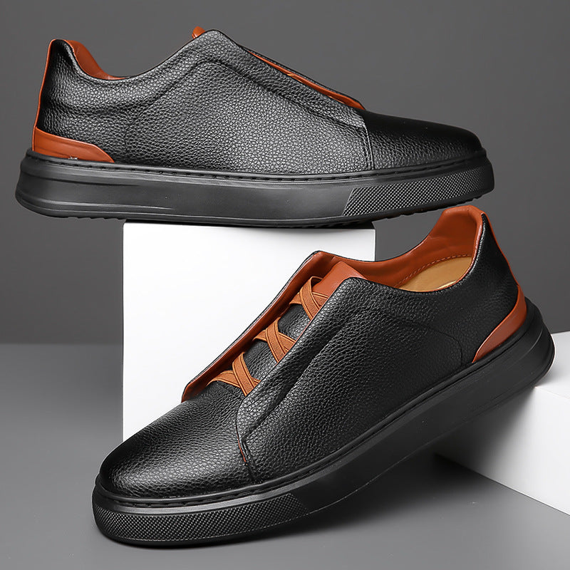 Black low-top sneakers with orange elastic lace and leather-look upper, angled view.