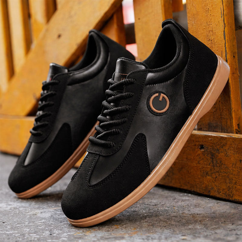 Black low-top lace-up sneakers with suede panels and circular logo