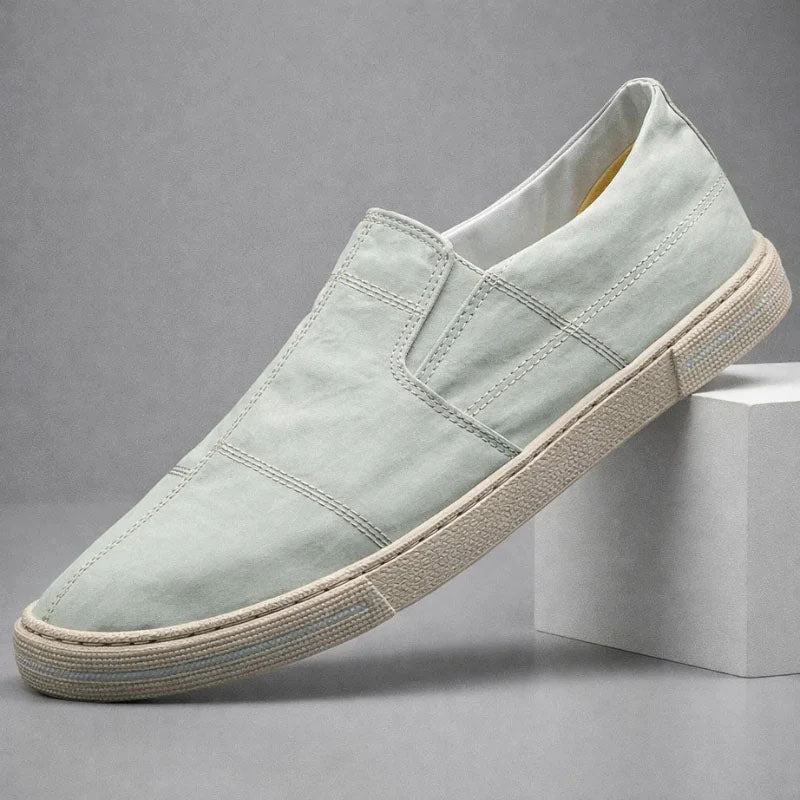Light blue slip-on canvas shoe with stitched cross panels and textured rubber sole