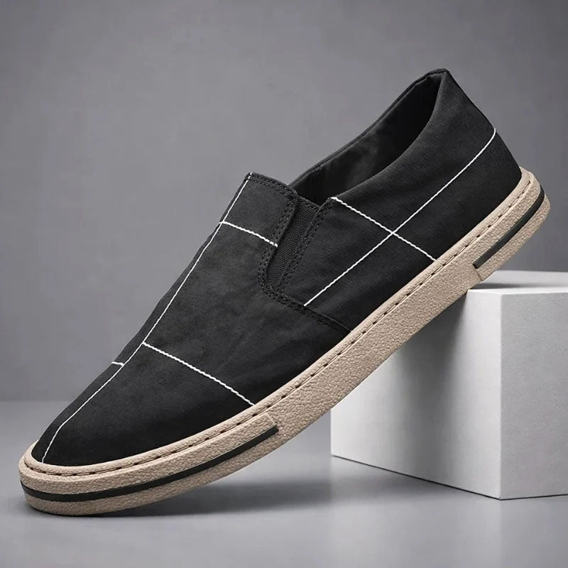Black slip-on canvas shoe with stitched cross panels and textured rubber sole