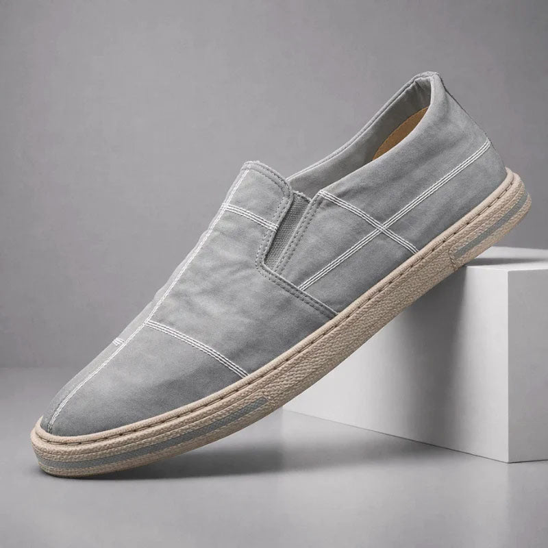 Gray slip-on canvas shoe with stitched cross panels and textured rubber sole