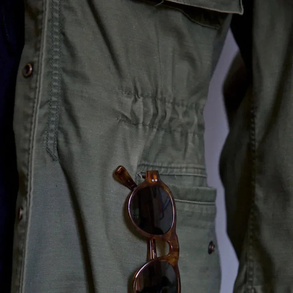 Olive field jacket close-up with drawstring waist and metal eyelets