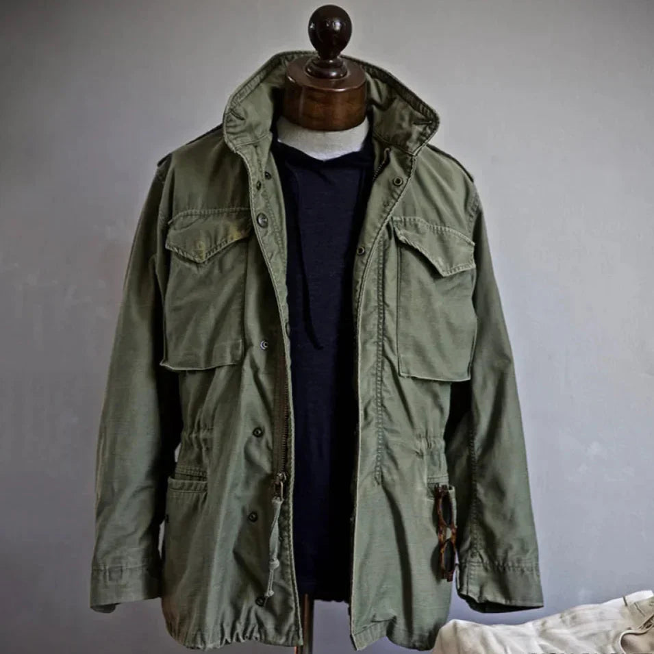 Olive field jacket on mannequin with flap chest pockets and button closure