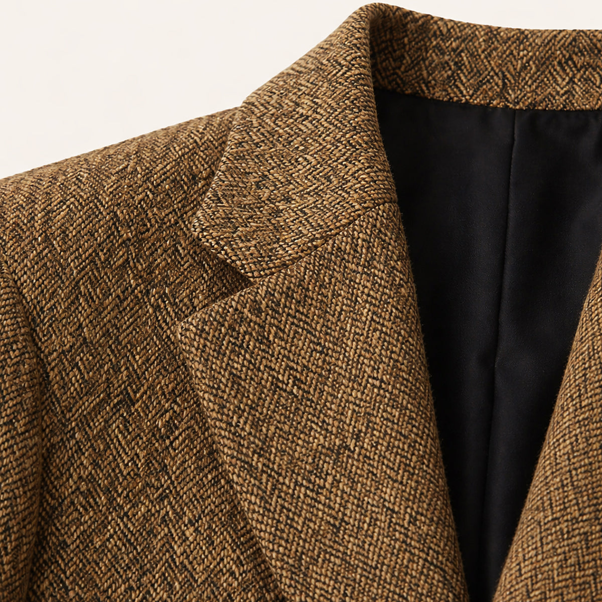 Close-up of brown herringbone tweed blazer lapel with black inner lining.