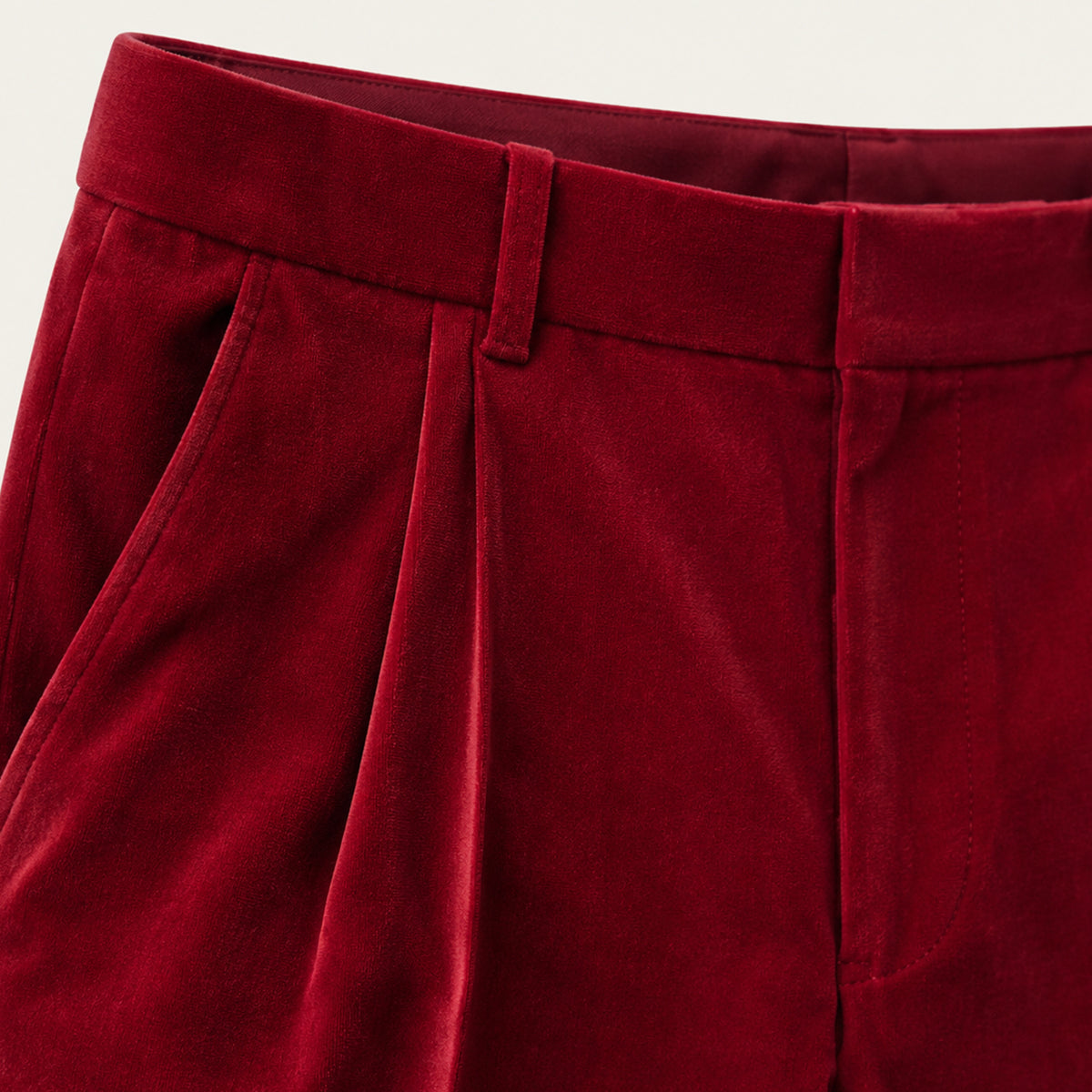 Burgundy velvet straight-fit pants close-up showing waistband and pleated front
