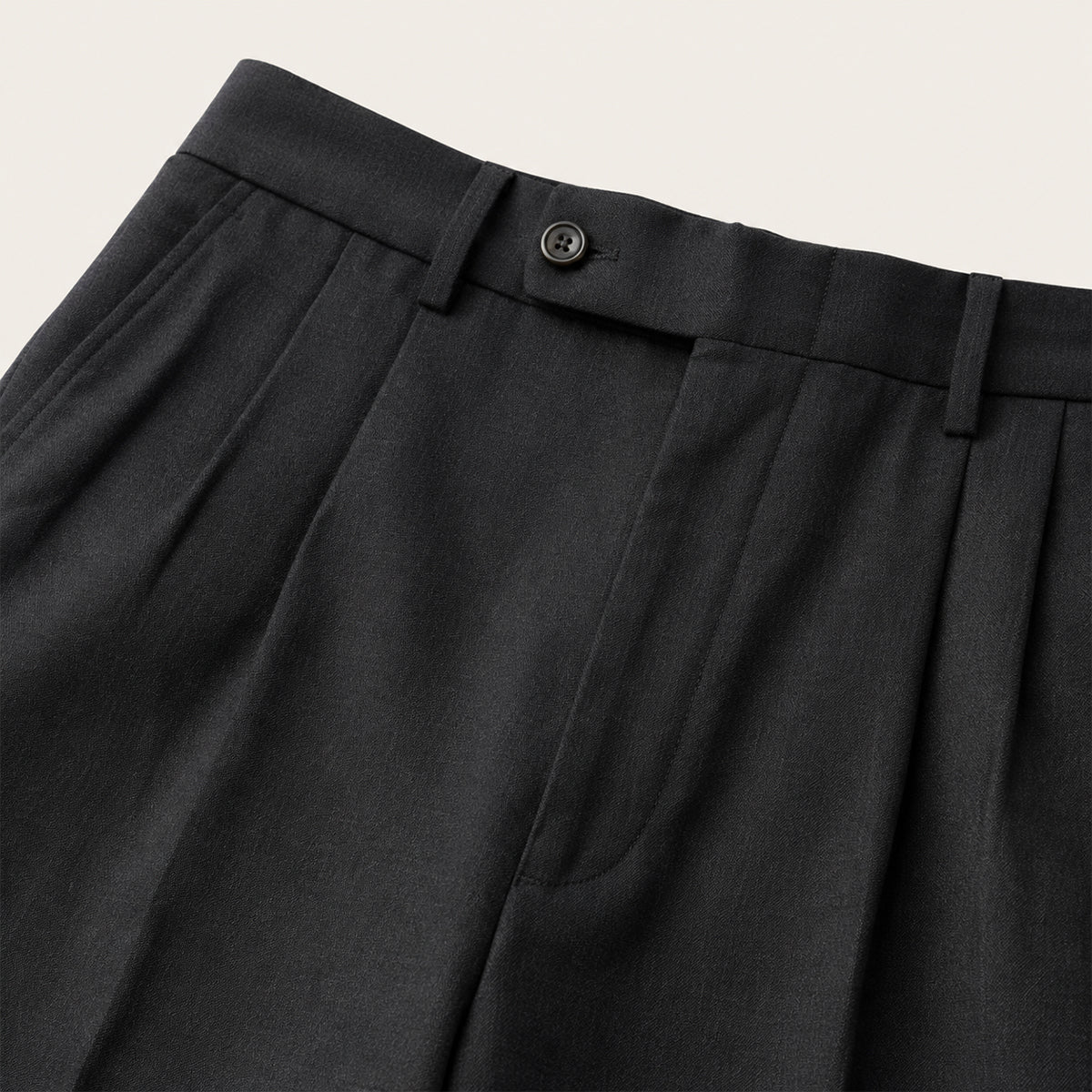 Men's black pleated pants waistband with button closure and belt loops