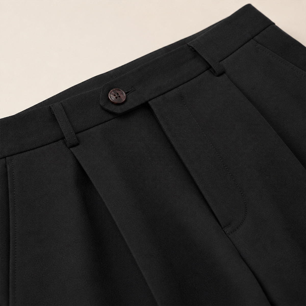 Black dress pants waistband with button closure and pleated front detail