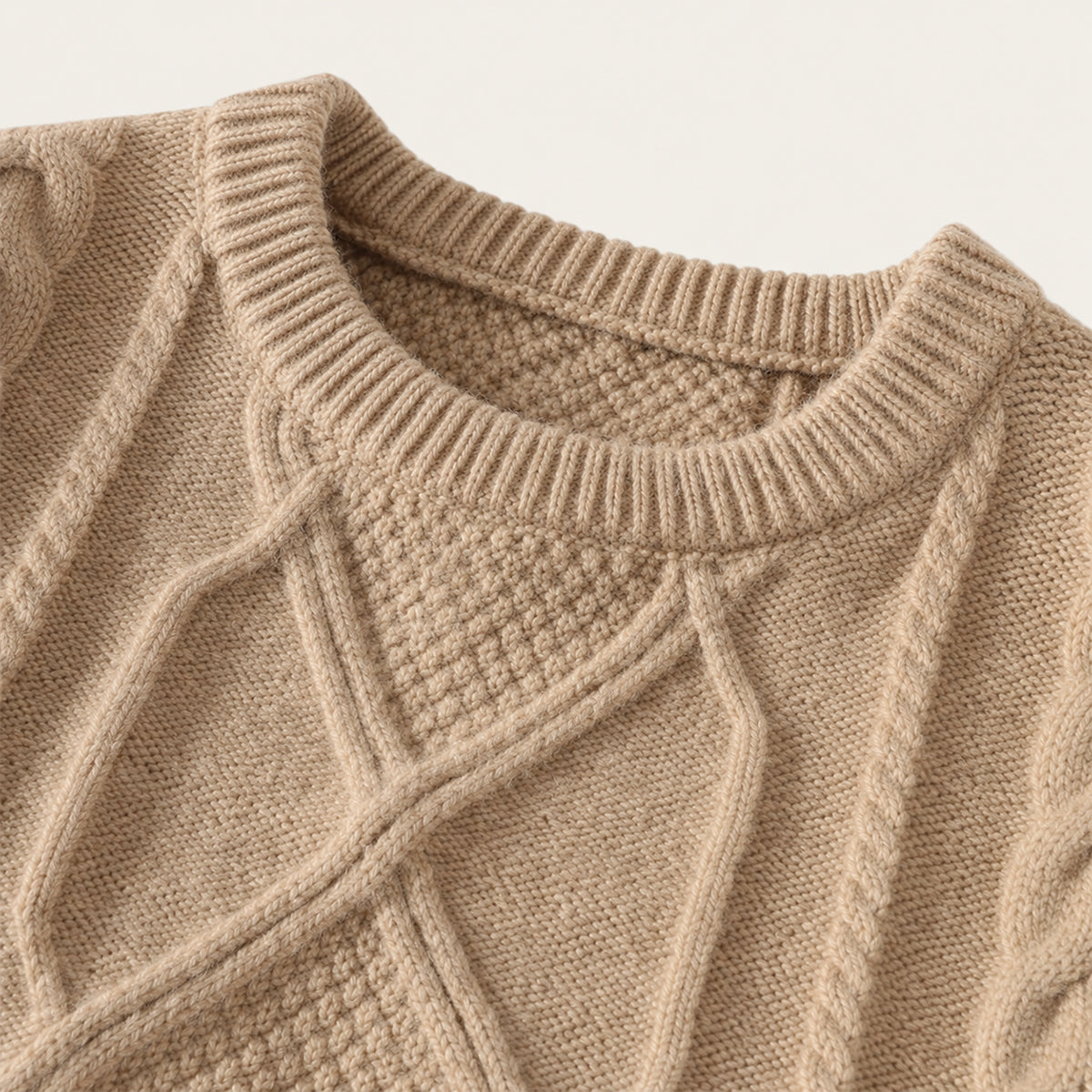 Close-up of beige cable knit sweater crew neck with ribbed collar and diamond motif